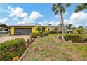 Bright yellow home featuring a metal roof, attached garage, and attractive landscaping at 1173 Brown St, Englewood, FL 34224