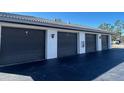 View of the gray garage doors, each numbered, and the black asphalt driveway at 150 Englewood Isles Pkwy # 201, Englewood, FL 34223