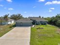 Wide shot of a well-maintained single story home with a long driveway leading to a spacious two car garage at 15251 Appleton Blvd, Port Charlotte, FL 33981