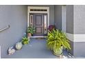 Close-up of a front door entrance with decorative plants and a cozy covered porch at 15251 Appleton Blvd, Port Charlotte, FL 33981