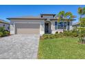 Inviting home featuring a well-manicured lawn, brick paved driveway, and covered front entryway at 1758 Saddlewood Cir, Port Charlotte, FL 33953