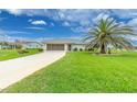 Well-manicured front yard with a mature palm tree in front of this single-story home at 2 Bunker Way, Rotonda West, FL 33947