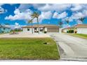 Charming single-story home featuring a well-manicured lawn, palm trees, and an attached two-car garage at 20 Bunker Way, Rotonda West, FL 33947
