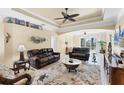Bright and airy living room featuring neutral tones, a ceiling fan, tray ceiling, and sliding glass doors to the outside at 284 Talquin Ct, Englewood, FL 34223