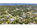 An aerial view showcases a neighborhood with mature trees and a beautiful lake in the distance at 5258 Grassland Ter, Port Charlotte, FL 33981