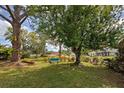 Scenic backyard featuring mature trees, green lawn, and a tranquil bench, perfect for relaxation at 587 Viridian St, Englewood, FL 34223