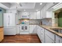 Bright kitchen with white cabinets, granite countertops, stainless steel appliances, and wood-look flooring at 107 Jose Gaspar Dr, Englewood, FL 34223