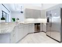 Bright kitchen features granite counters, stainless steel appliances, and light gray cabinets at 12605 Bacchus Rd, Port Charlotte, FL 33981