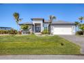 Beautiful contemporary home with a well-manicured lawn, lush landscaping, and a two-car garage at 15498 Seafoam Cir, Port Charlotte, FL 33981