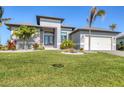 Charming one-story home featuring an attractive front yard with lush green grass and palm trees at 15498 Seafoam Cir, Port Charlotte, FL 33981