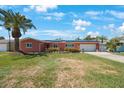 Charming coral home featuring a two-car garage, lush lawn, solar panels, and tropical landscaping at 1694 Harbor W Cir, Largo, FL 33770