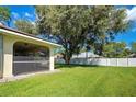 Spacious backyard featuring a screened lanai, large shade tree, and a white privacy fence at 18174 Dickens Ave, Port Charlotte, FL 33954