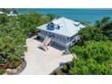 Stunning coastal home with a metal roof, lush landscaping, and a light blue exterior at 19 Grouper Hole Dr, Boca Grande, FL 33921