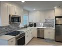 Modern kitchen with stainless steel appliances, white cabinets, and sleek backsplash at 2405 N Beach Rd # 10, Englewood, FL 34223