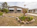 Tan home with tidy front lawn and landscaped flowerbed with a sign reading 'Spring' at 3021 Holly Ave, Englewood, FL 34224