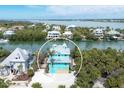 Aerial view of a blue home surrounded by lush greenery and waterfront access at 50 Tarpon Way, Placida, FL 33946