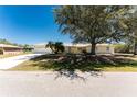 Charming one-story home with a circular driveway, well-maintained lawn, and mature shade tree at 7328 Yardley St, Englewood, FL 34224
