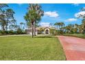 A well-manicured lawn and red brick driveway complement the home's exterior, surrounded by palm trees and blue skies at 915 Park Place Dr, Englewood, FL 34223