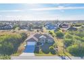 An aerial view of a single-story home in a quiet neighborhood surrounded by lush greenery at 9219 Newnan Cir, Port Charlotte, FL 33981