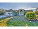 Inviting single-story home with a lush lawn, palm trees, and a two-car garage at 9219 Newnan Cir, Port Charlotte, FL 33981