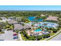 Aerial view of a community clubhouse, pool, tennis courts and lake surrounded by trees and other homes at 1104 Yosemite Dr, Englewood, FL 34223