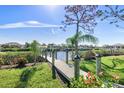 Scenic waterfront view of a wooden dock extending into a tranquil canal under a clear blue sky at 14564 Gaspar Loop, Port Charlotte, FL 33981