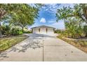 Spacious three-car garage with a large driveway, surrounded by mature trees and landscaping at 182 Rotonda W Blvd # B, Rotonda West, FL 33947