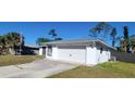 Home with a two-car garage, a well-maintained lawn, and a long concrete driveway at 2259 Lee Ter, Port Charlotte, FL 33952