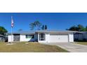 Charming single-story home featuring stone accents, an American flag, a well-maintained lawn, and a two-car garage at 2259 Lee Ter, Port Charlotte, FL 33952