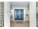 Inviting front entrance featuring a blue door flanked by sidelight windows and stylish hanging lanterns at 235 Caddy Rd, Rotonda West, FL 33947