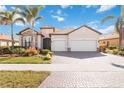 Beautiful home featuring a tile roof, three-car garage, paver driveway and mature landscaping at 25207 Spartina, Venice, FL 34293