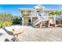 Beautiful two-story home with white exterior, tropical plants, and decorative dolphin statue in the front yard at 62 Tarpon Way, Placida, FL 33946