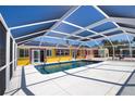 Screened-in pool featuring a tile deck is surrounded by the yellow and orange home at 741 W Perry St, Englewood, FL 34223