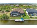 Aerial view of a backyard with a screened pool, waterfront access, and a private dock with seating and an umbrella at 8304 Antwerp Cir, Port Charlotte, FL 33981