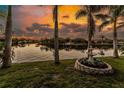 Beautiful canal view with a fountain and palm trees against a backdrop of a vibrant sunset at 9325 Saint Paul Dr, Port Charlotte, FL 33981