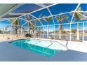 Relaxing screened-in pool with a view of the canal, surrounded by beautiful palm trees and an area for outdoor seating at 9325 Saint Paul Dr, Port Charlotte, FL 33981
