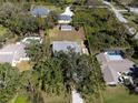 Aerial view of a property showcasing a spacious lot with lush greenery, a storage shed, and neighboring homes with pools at 1104 Larchmont Dr, Englewood, FL 34223