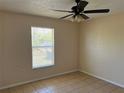 Cozy bedroom with a ceiling fan, neutral walls, tile flooring, and a bright window at 11090 Mcfadden Ave, Englewood, FL 34224