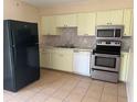 Efficient kitchen with stainless steel appliances, light yellow cabinets, and ample counter space at 11090 Mcfadden Ave, Englewood, FL 34224