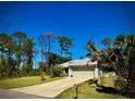Well-maintained single-story home with a two-car garage, mature trees, and a spacious driveway at 13244 Doral Ave, Port Charlotte, FL 33953