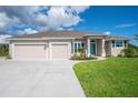 Charming home featuring a three-car garage, well-manicured lawn, and a welcoming bright blue front door at 13252 Keystone Blvd, Port Charlotte, FL 33981