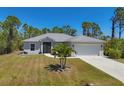 Charming home featuring a gray roof, complemented by a well-maintained lawn and a spacious two-car garage at 15613 Alsask Cir, Port Charlotte, FL 33981