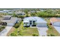 Stunning aerial view of a white waterfront home with a metal roof, lush landscaping, and a paver driveway at 18610 Ayrshire, Port Charlotte, FL 33981