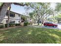 A well maintained condo building with mature trees, manicured lawn and adjacent parking at 19505 Quesada Ave # B202, Port Charlotte, FL 33948