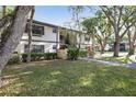 Scenic view of the condo building surrounded by beautiful, mature trees and lush green lawn at 19505 Quesada Ave # B202, Port Charlotte, FL 33948