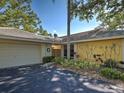 A charming yellow house features a two-car garage, mature shrubs, and an inviting, shaded entrance at 220 Southampton Drive # 325, Venice, FL 34293