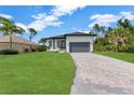 Beautiful single-Gathering home featuring a manicured lawn and brick paver driveway under a sunny sky at 280 Antis Dr, Rotonda West, FL 33947