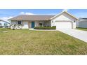 A well-maintained front lawn leads to a charming home with a bright blue front door and attached garage at 5266 Cooper Ter, Port Charlotte, FL 33981