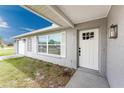Inviting front entrance featuring a white door, light gray stucco, and decorative window shutters at 6375 Coniston St, Port Charlotte, FL 33981
