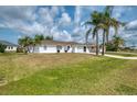 Inviting home with a well-kept lawn, mature palm trees, and a concrete driveway at 7215 Brookhaven Ter, Englewood, FL 34224